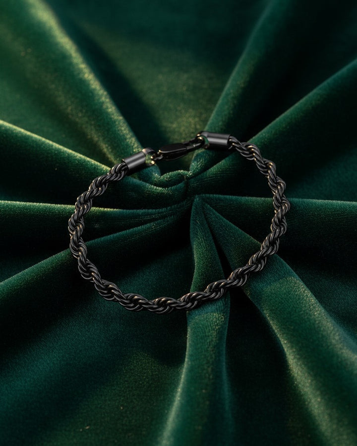 Elli Jewellery black rope chain bracelet with a textured design resting on a dark green velvet background.