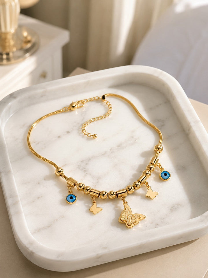 Elli Jewellery gold plated necklace featuring butterfly charms and blue evil eye pendants on a delicate mesh chain.