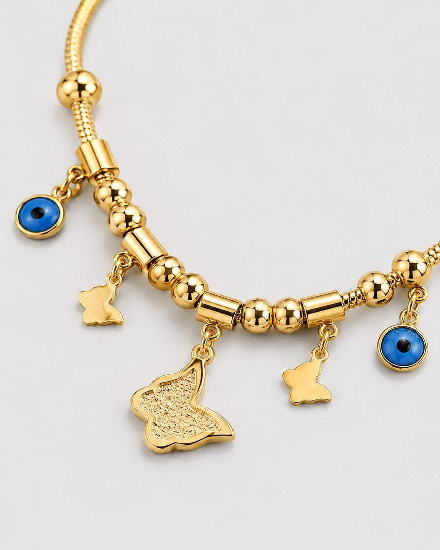 Elli Jewellery gold plated necklace featuring butterfly charms and blue evil eye pendants on a beaded mesh chain