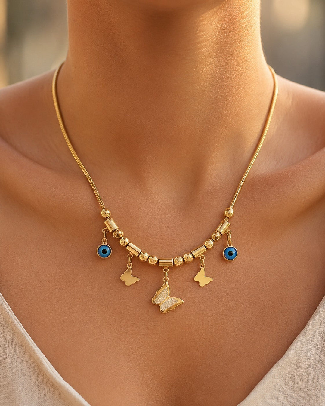 Elli Jewellery gold plated necklace featuring butterfly charms and blue evil eye pendants on a fine mesh chain