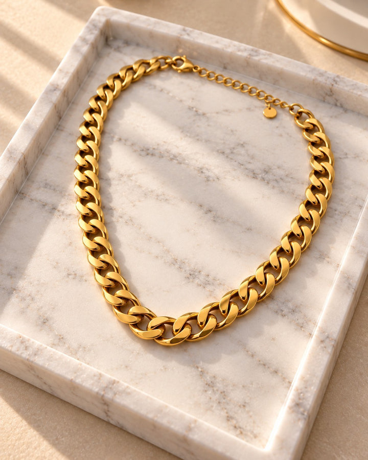 Elli Jewellery bold chunky gold-plated Cuban link chain necklace resting on a white marble tray