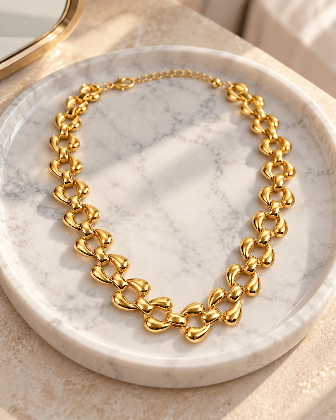 Elli Jewellery chunky gold-plated curb chain necklace with polished rounded links resting on a marble tray.