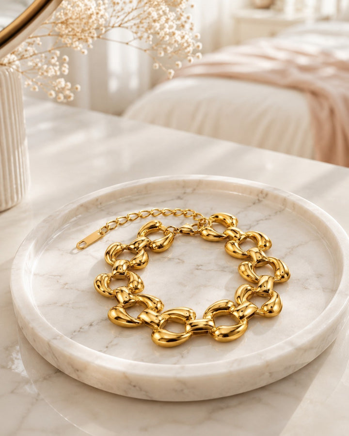 Elli Jewellery chunky oval link bracelet in 18ct gold plated finish resting on a white marble tray.