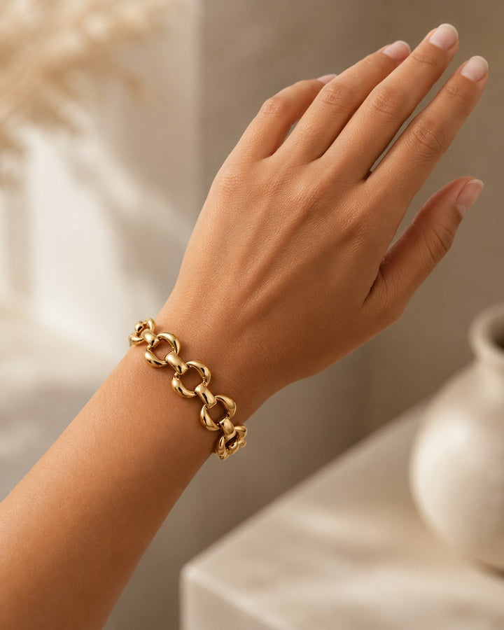 Elli Jewellery chunky oval link bracelet in 18ct gold plated finish worn on a woman's wrist
