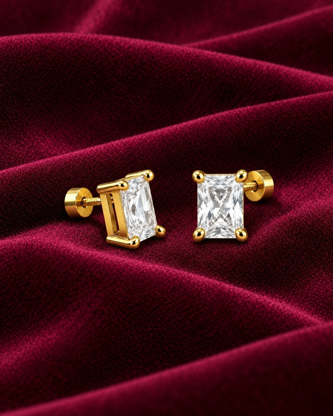 Elli Jewellery gold-plated stud earrings featuring emerald-cut cubic zirconia stones on a deep red velvet background.