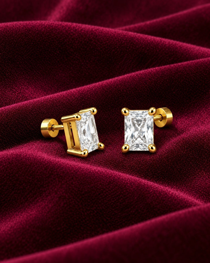 Elli Jewellery gold-plated stud earrings featuring emerald-cut cubic zirconia stones on a deep red velvet background.