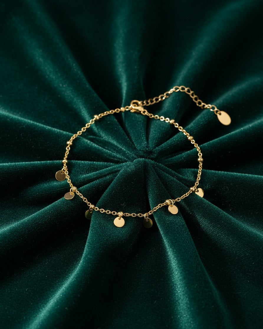 Elli Jewellery gold toned anklet featuring delicate chain with small hanging ball and disc charms on green velvet
