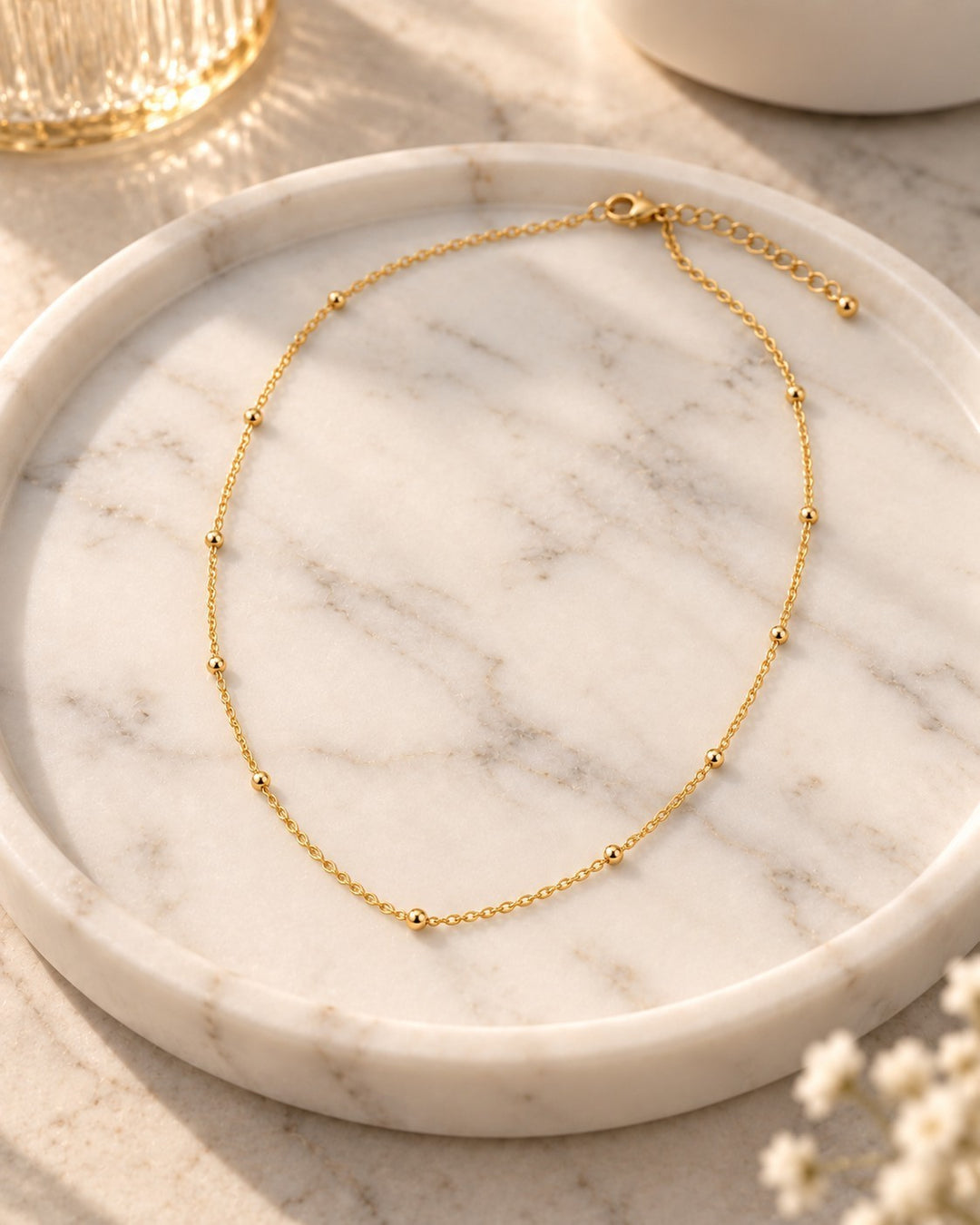 Elli Jewellery gold plated dainty ball bead chain necklace resting on a white marble tray