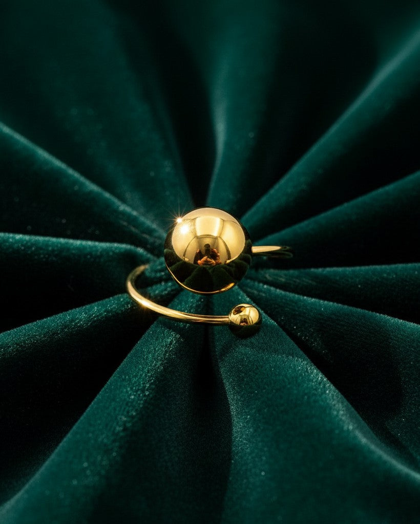 Elli Jewellery gold plated waterproof open ring featuring a large polished ball bead on a dark green velvet background