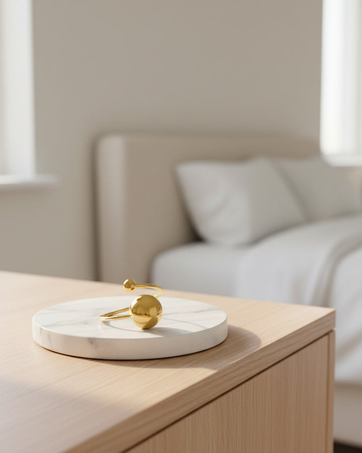 Elli Jewellery gold plated waterproof open ball bead statement ring resting on a white marble display stand.