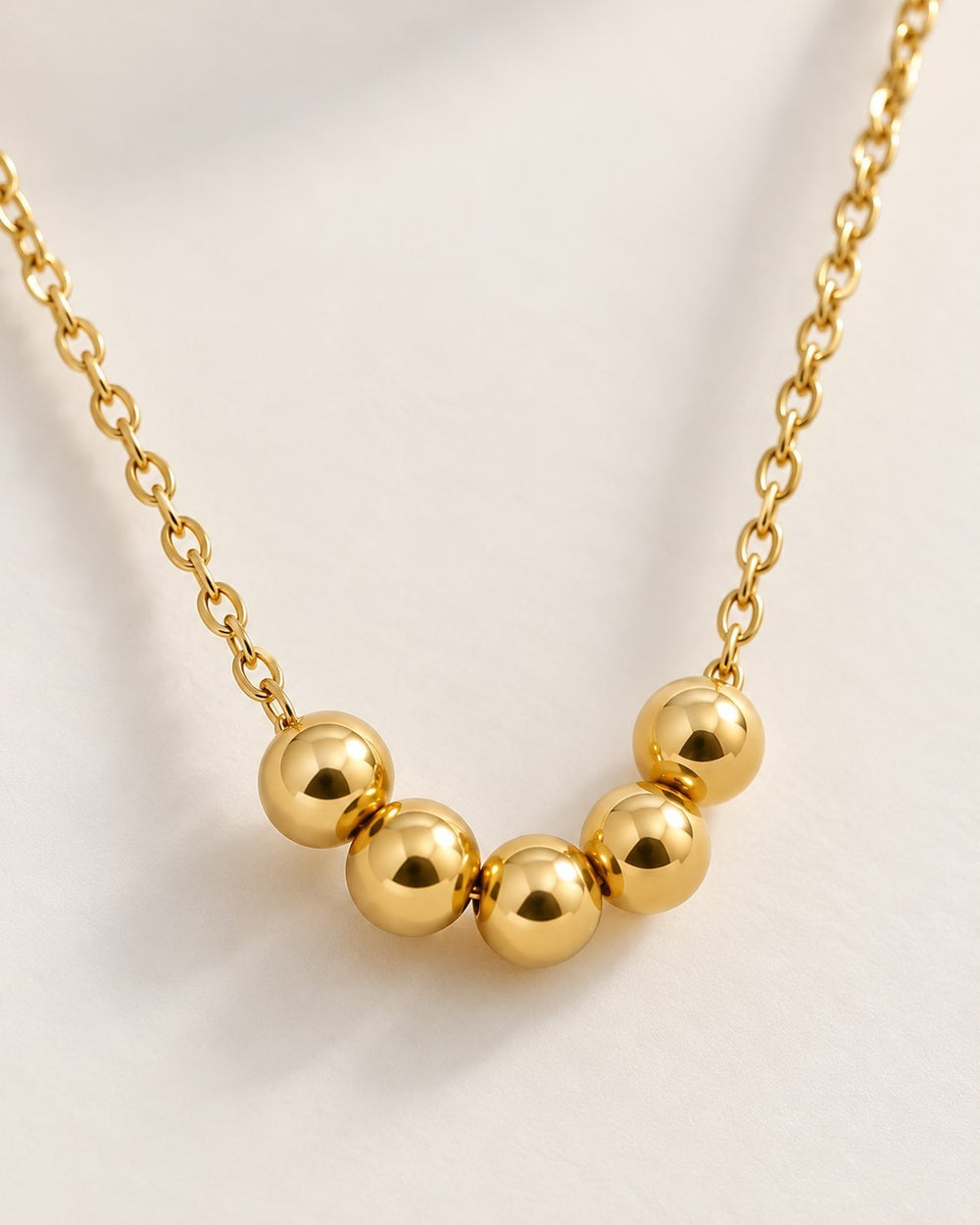 Elli Jewellery gold plated waterproof necklace featuring five polished spherical ball charms on a delicate chain.