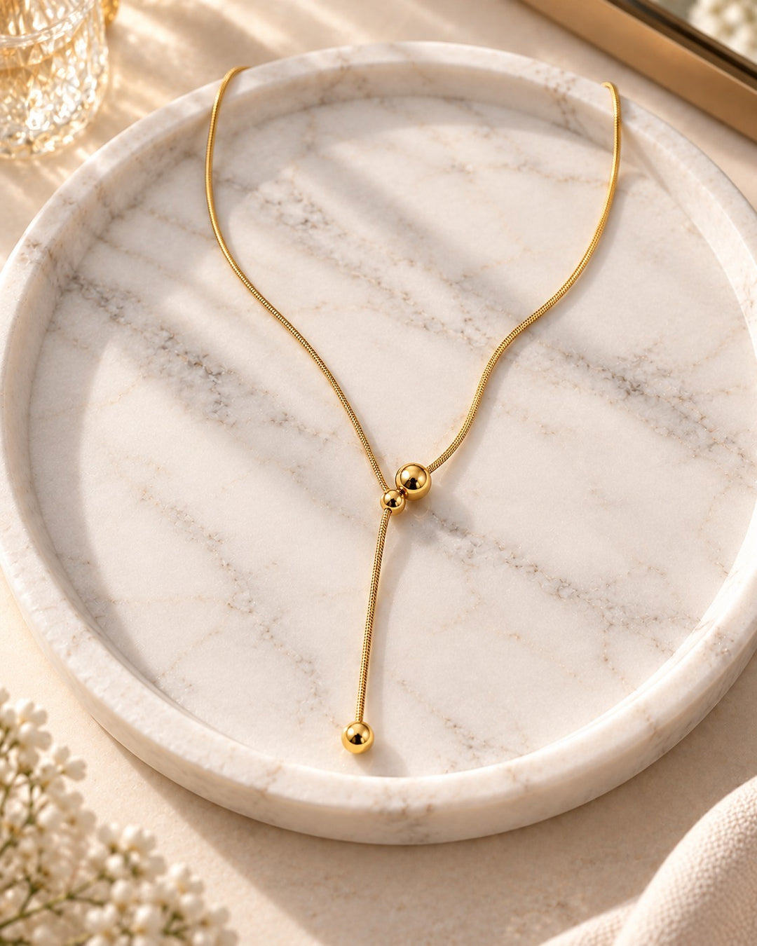 Elli Jewellery gold plated waterproof minimalist necklace featuring a delicate chain and hanging ball pendant design.
