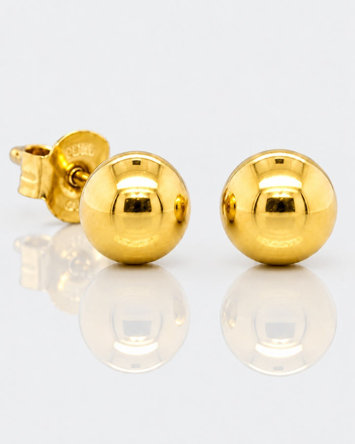 Elli Jewellery gold plated minimalist ball stud earrings with a polished finish on a reflective white surface.