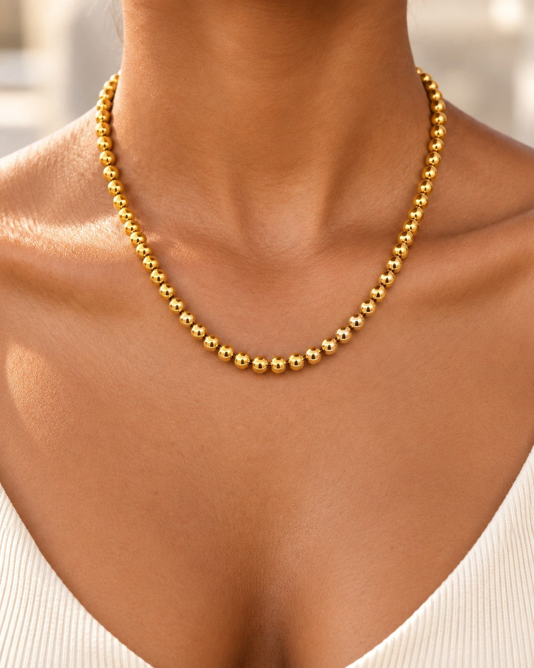 Elli Jewellery gold-plated waterproof beaded ball chain necklace worn on a woman's neck.