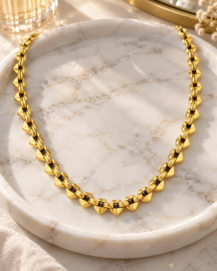 Elli Jewellery 18ct gold plated brass spherical beaded chain necklace displayed on a marble tray.