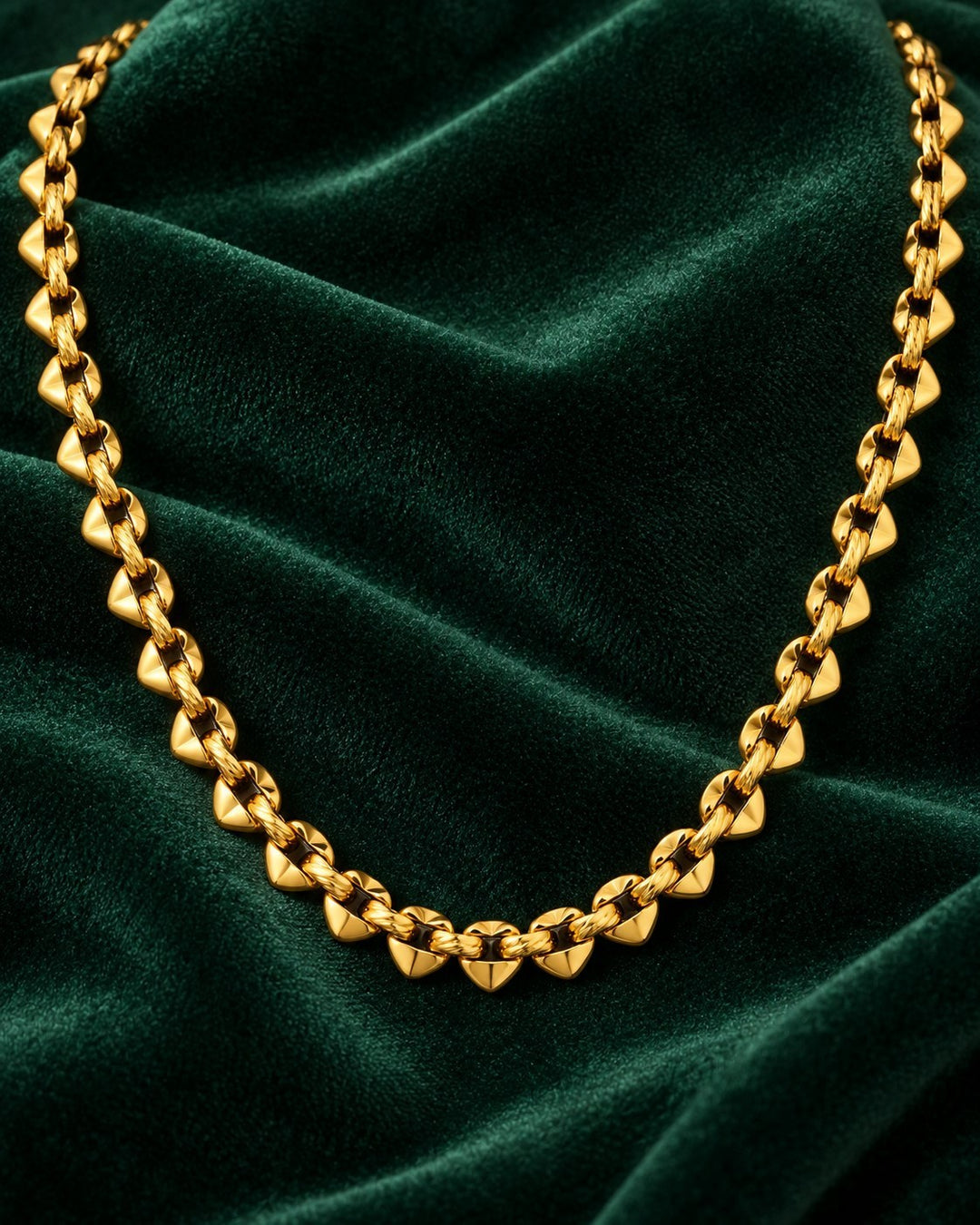 Elli Jewellery spherical beaded chain necklace in 18ct gold plated brass, displayed on a dark green velvet background.
