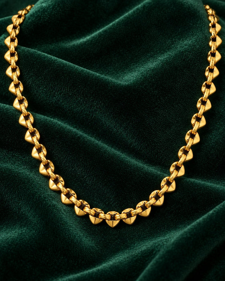Elli Jewellery spherical beaded chain necklace in 18ct gold plated brass, displayed on a dark green velvet background.