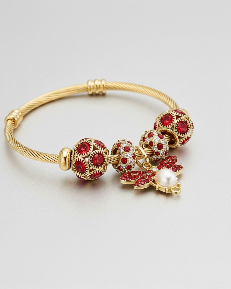 Elli Jewellery gold plated hinged bangle featuring a bee charm with red crystals and a pearl accent.