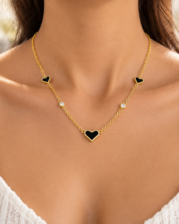 Elli Jewellery gold plated necklace featuring black heart pendants and sparkling crystals worn on a woman's neck