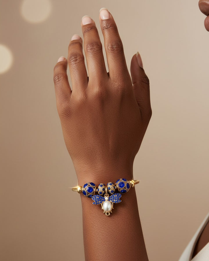 Elli Jewellery gold plated adjustable bangle featuring a blue enamel butterfly charm with a central pearl accent