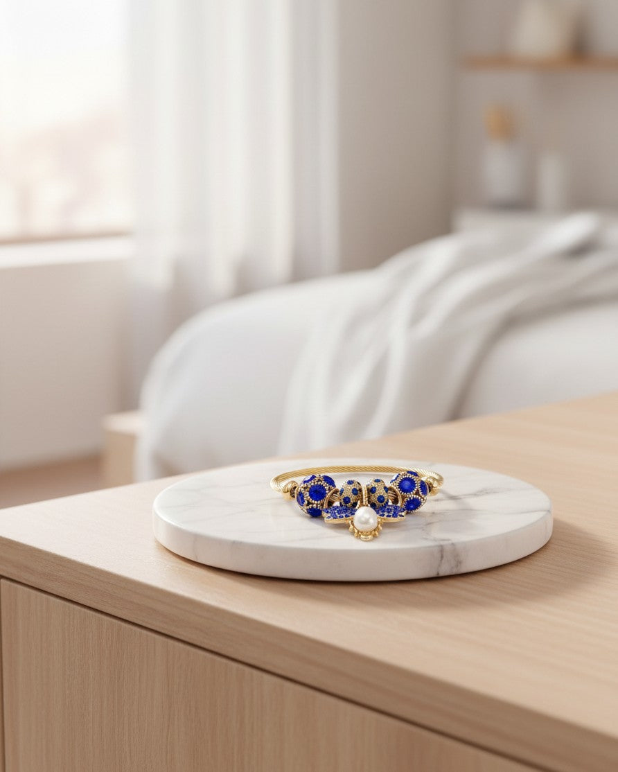 Elli Jewellery gold plated adjustable bangle featuring a blue enamel butterfly charm and a central pearl accent.