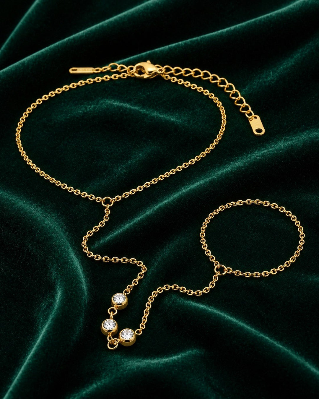 Elli Jewellery gold plated boho hand chain bracelet with crystal accents on a dark green velvet background