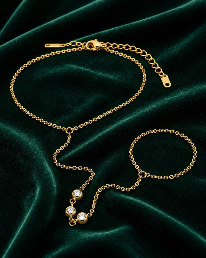 Elli Jewellery gold plated boho hand chain bracelet with crystal accents on a dark green velvet background
