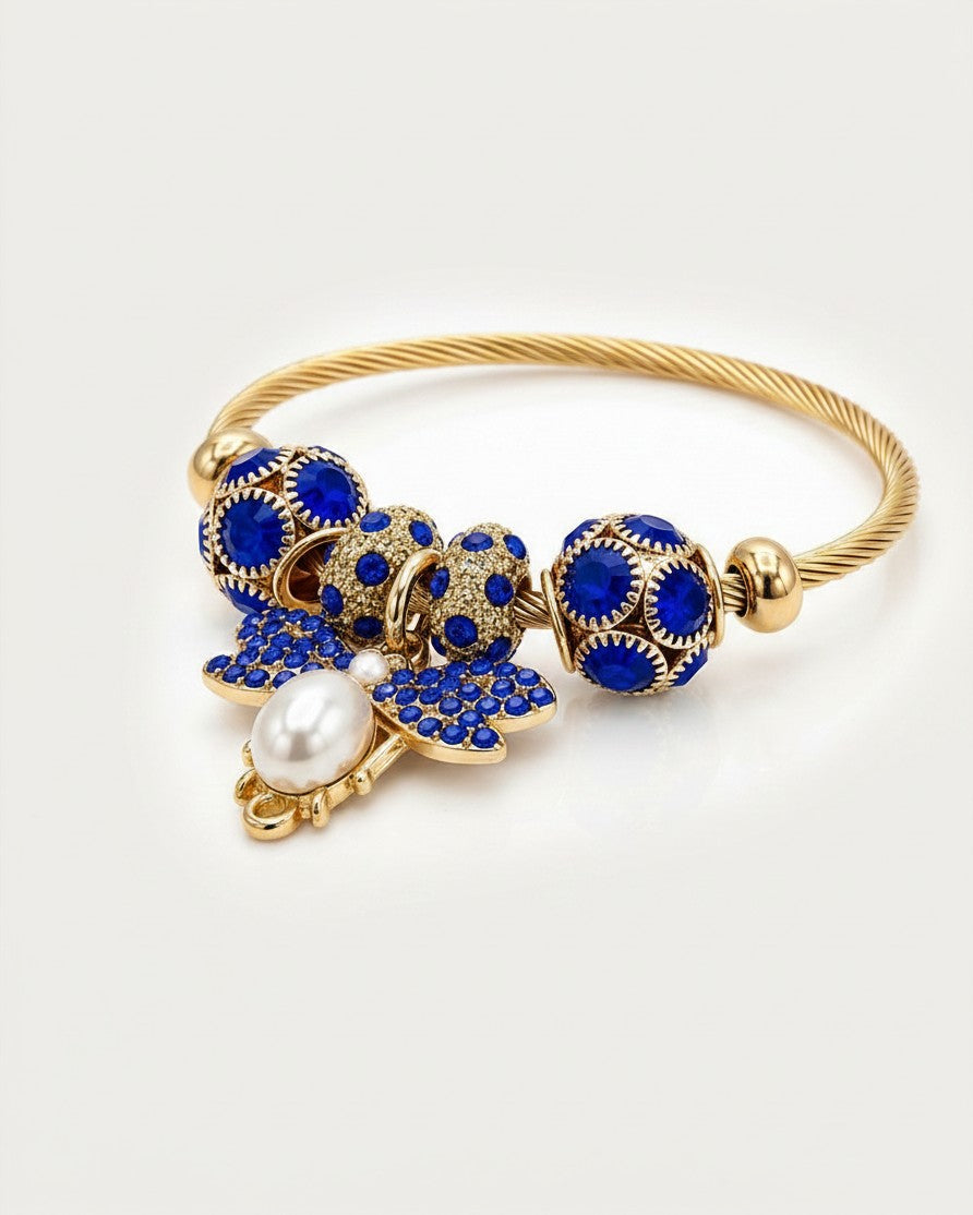 Elli Jewellery gold plated adjustable bangle featuring a blue enamel butterfly charm, pearl accent, and crystal beads.