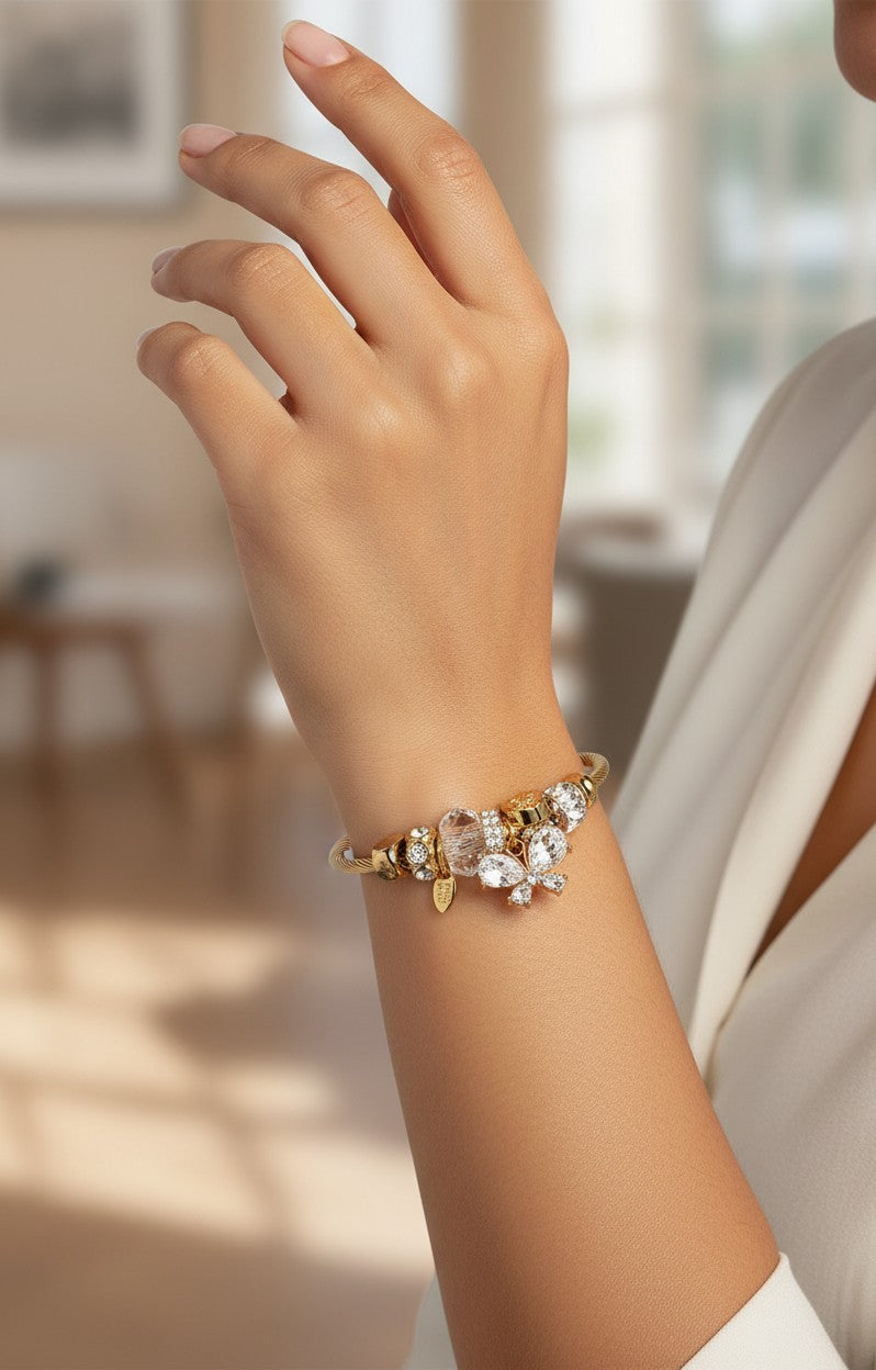 Elli Jewellery gold plated bangle featuring a sparkling diamanté butterfly charm worn on a woman's wrist