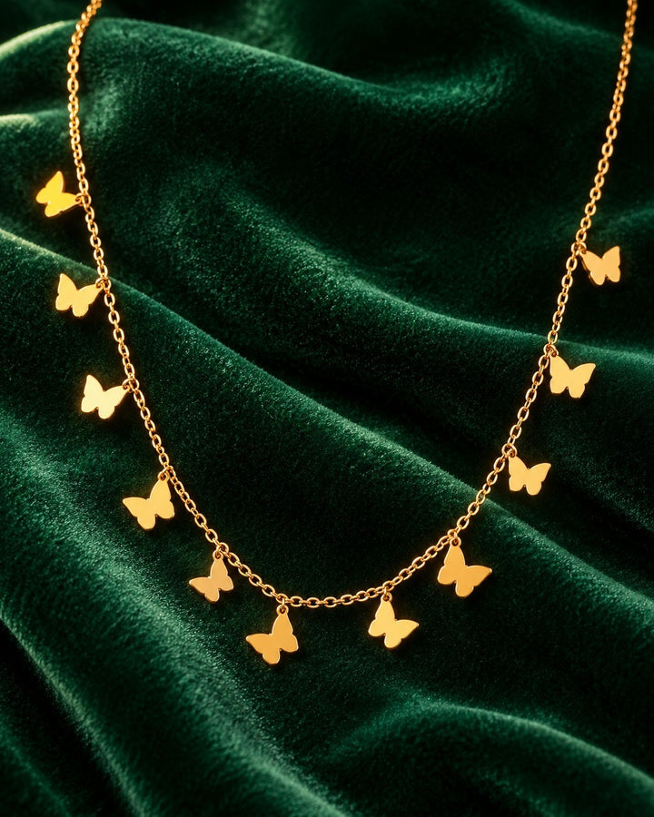 Elli Jewellery gold plated delicate chain necklace featuring multiple small butterfly charms on green velvet fabric.
