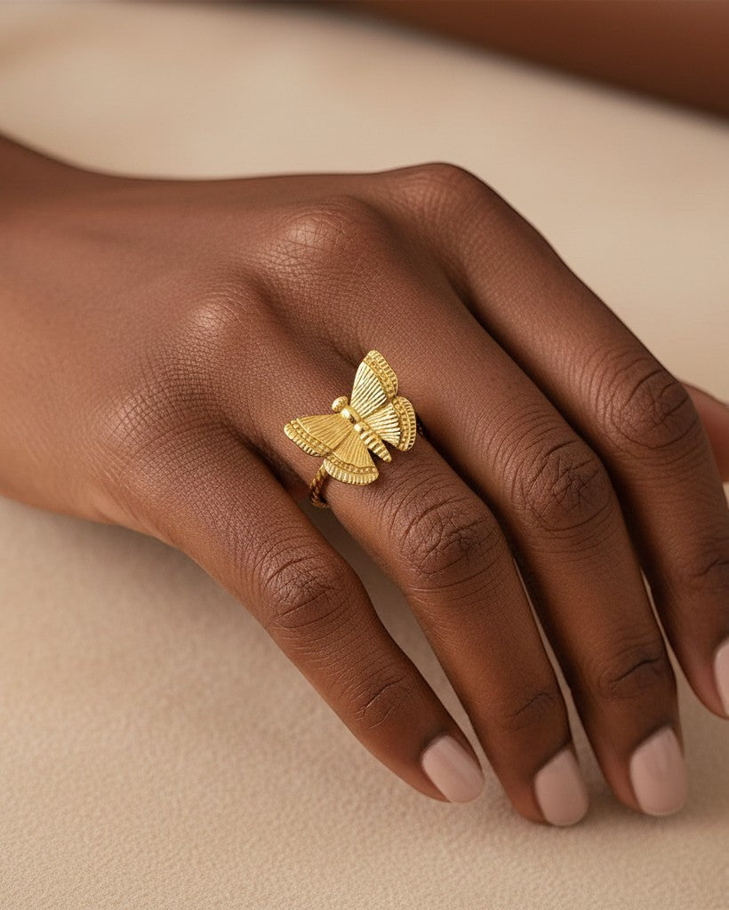 Elli Jewellery gold plated open butterfly ring with textured wings worn on a finger against a neutral background