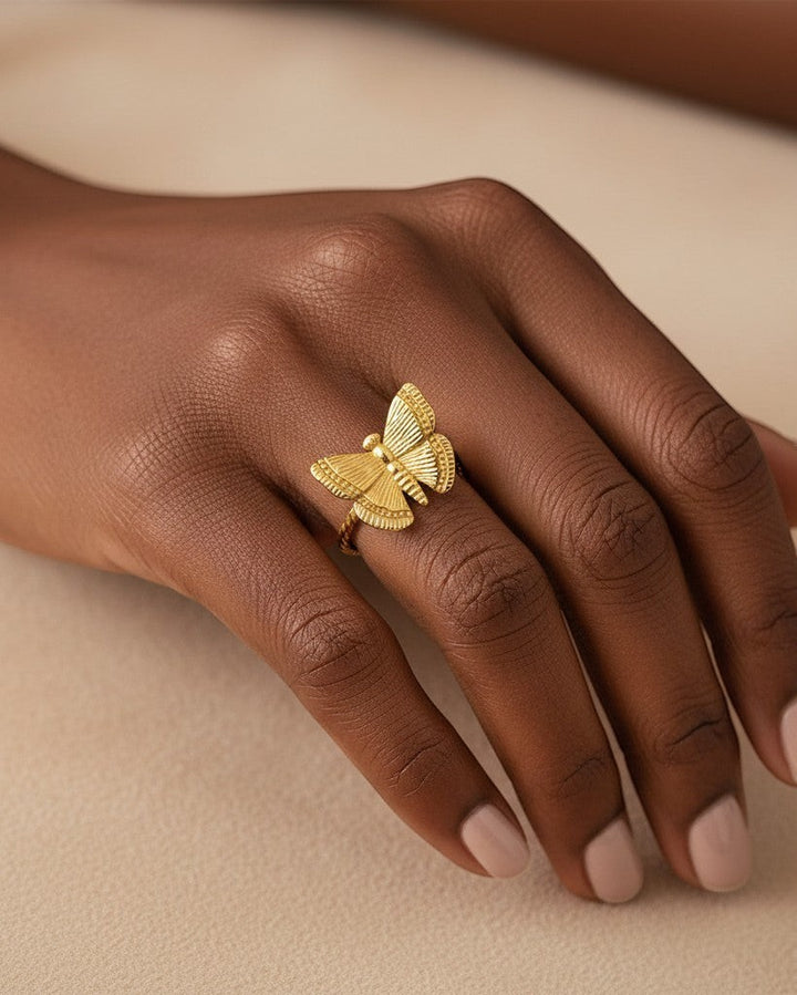 Elli Jewellery gold plated open butterfly ring with textured wings worn on a finger against a neutral background