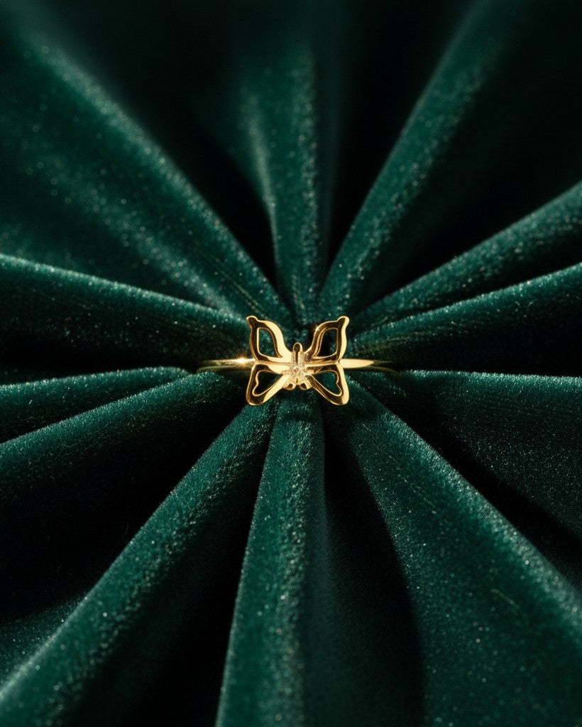 Elli Jewellery gold plated butterfly statement ring with crystal accents on a dark green velvet background