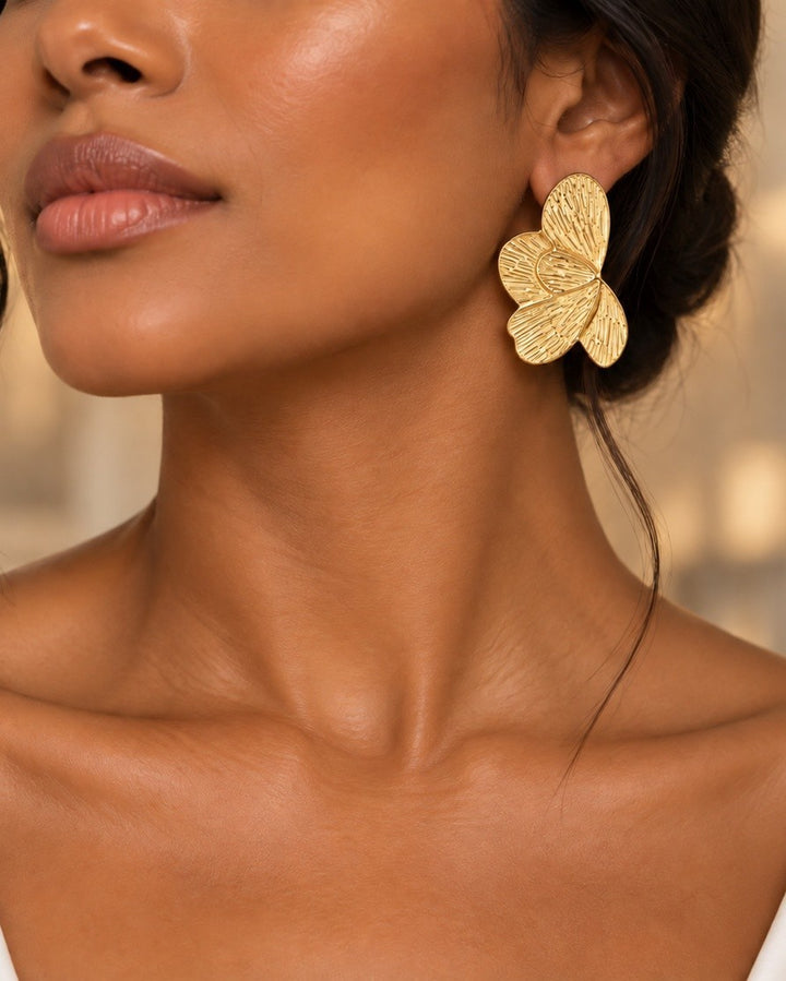 Elli Jewellery sculptural butterfly stud earrings in 18ct gold plated metal with etched linear texture on a model