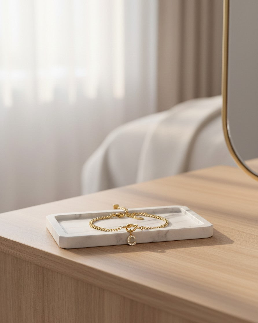Elli Jewellery gold plated waterproof C initial bracelet with sparkling diamanté crystals on a marble tray