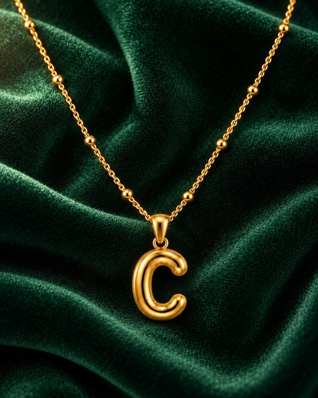 Elli Jewellery gold plated waterproof chunky chain necklace featuring a bold letter C initial pendant on green velvet