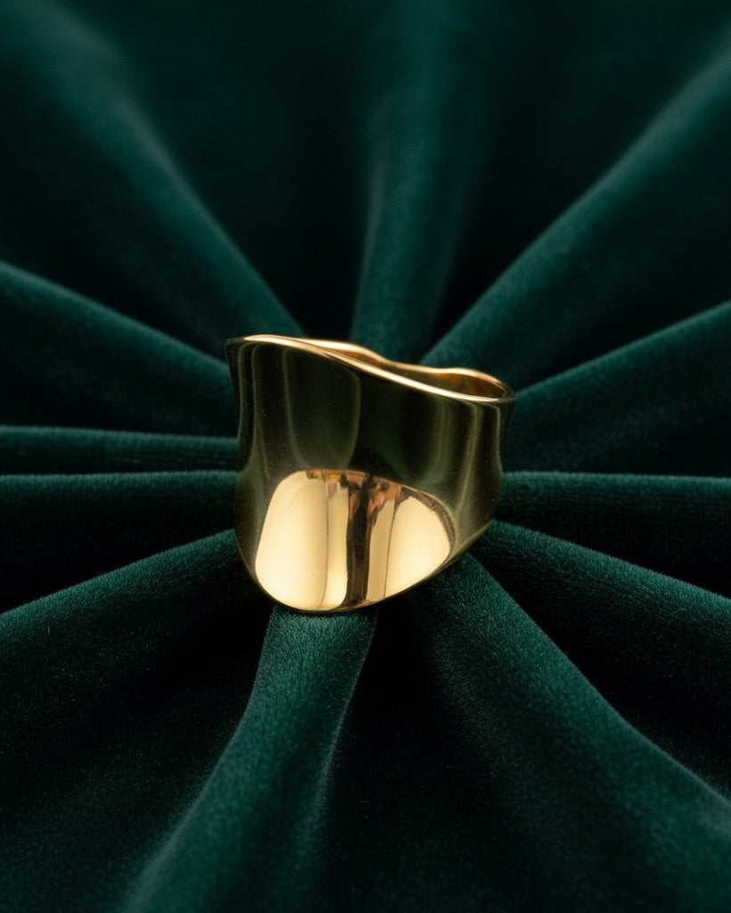 Elli Jewellery gold plated brushed cambered open cuff ring on a dark green velvet background.