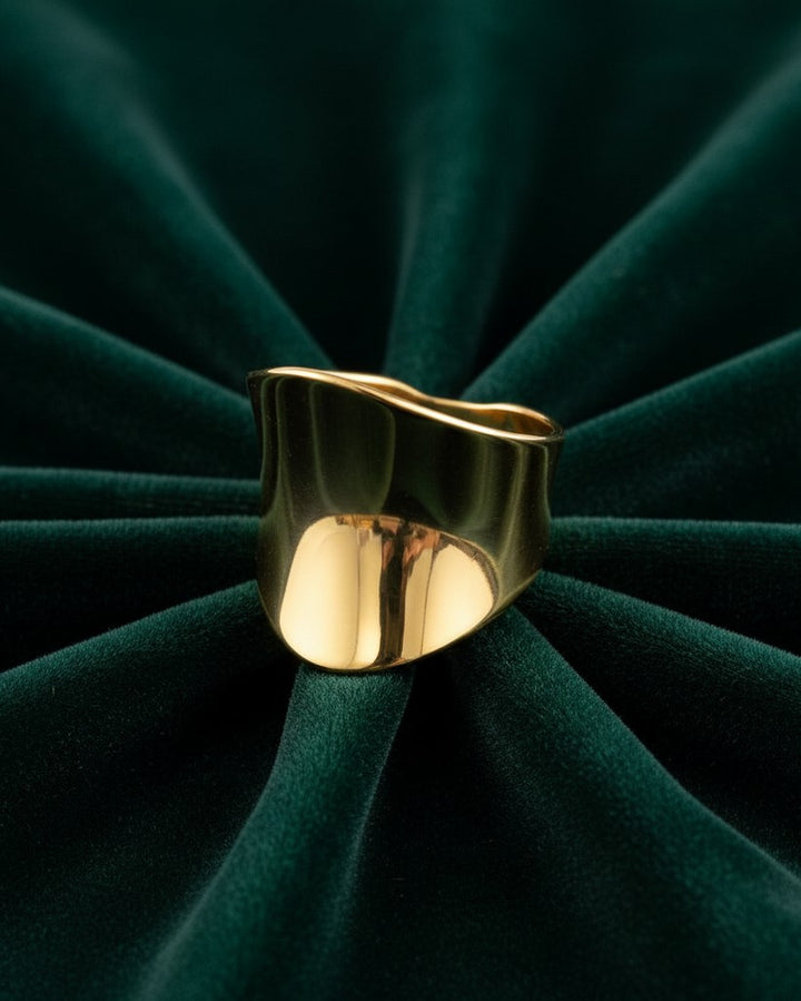 Elli Jewellery gold plated brushed cambered open cuff ring on a dark green velvet background.