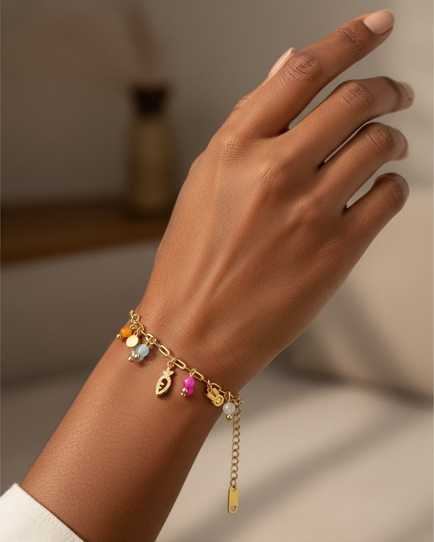 Elli Jewellery gold plated charm bracelet with a carrot charm and colorful beads worn on a woman's wrist