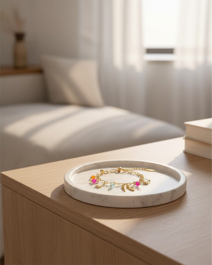 Elli Jewellery gold plated waterproof charm bracelet with playful carrot and colorful beads on a marble tray