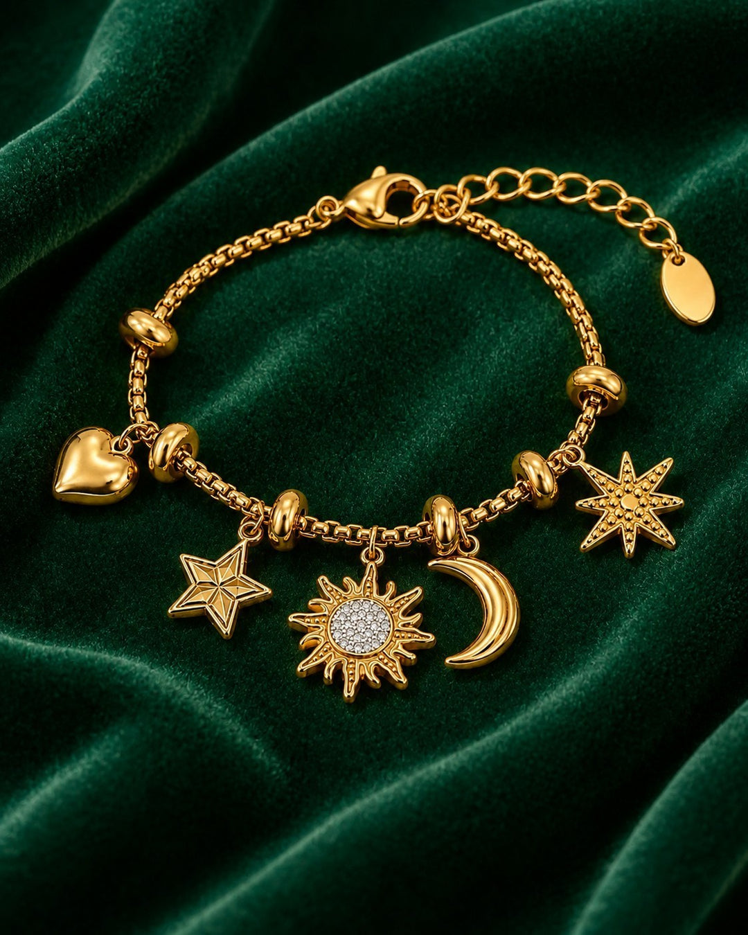 Elli Jewellery gold plated charm bracelet featuring sun, moon, star, and heart pendants on a green velvet background.
