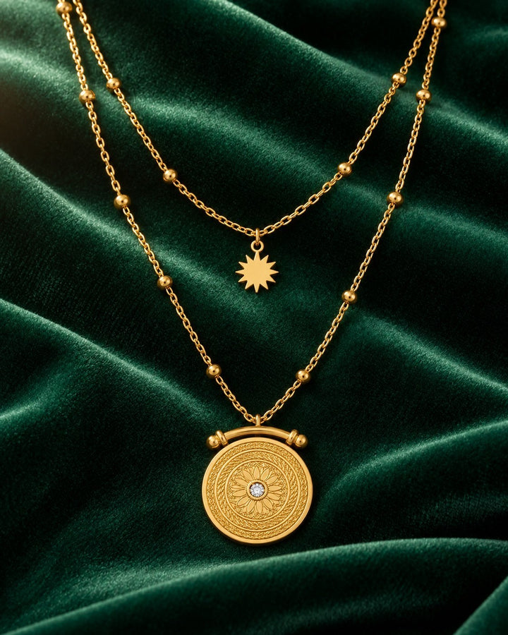 Elli Jewellery gold plated double layered necklace with celestial sun and sundial pendants on green velvet background