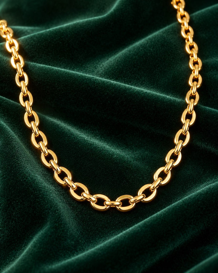 Elli Jewellery gold-plated chain choker necklace with oval links resting on a luxurious dark green velvet background.