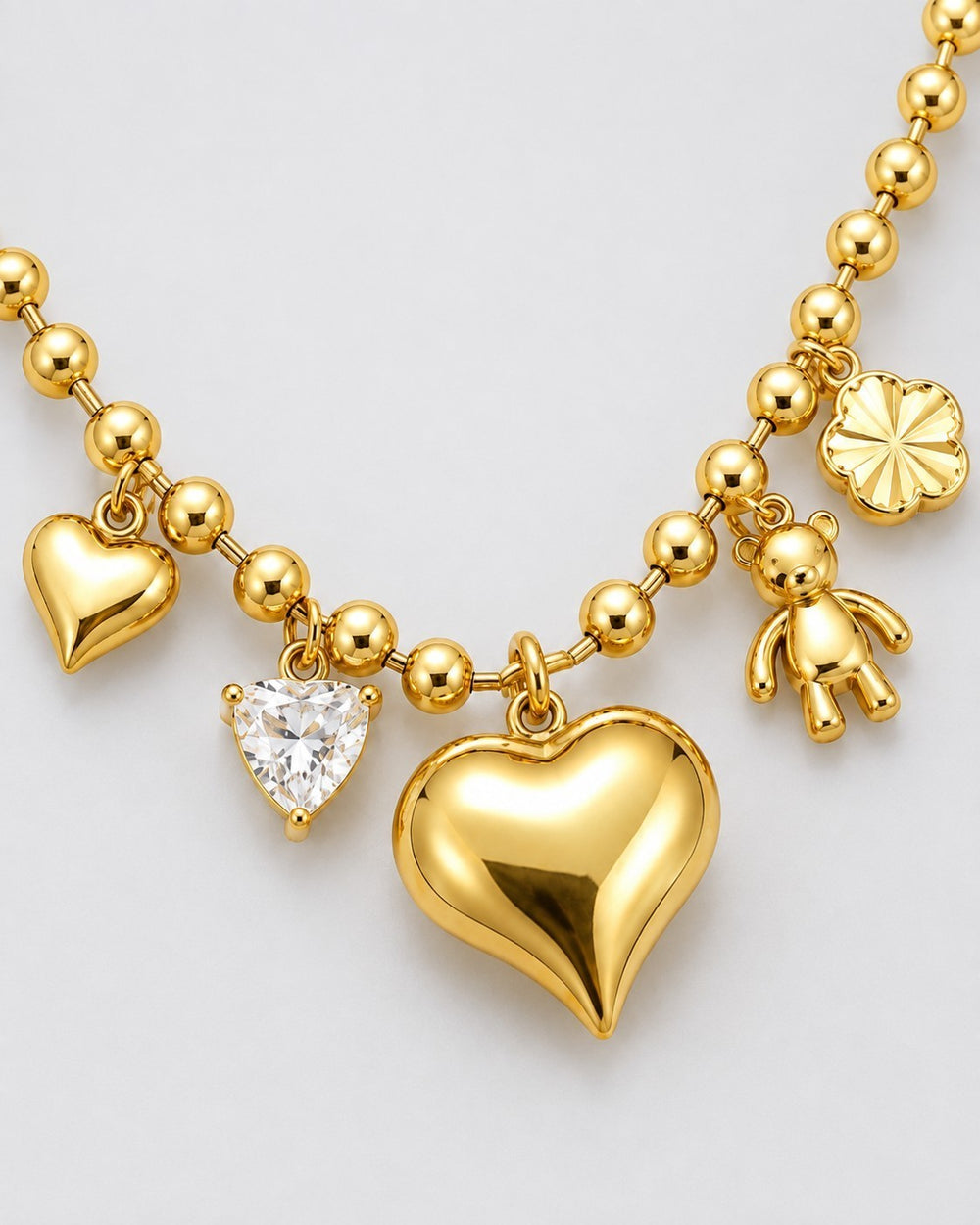 Elli Jewellery gold plated stainless steel charm necklace featuring heart, teddy bear, and flower charms on bead chain