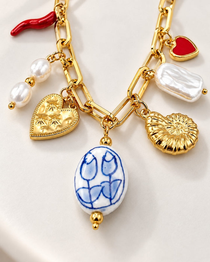 Elli Jewellery gold chain charm bracelet featuring pearl, heart, shell, and blue floral ceramic charms