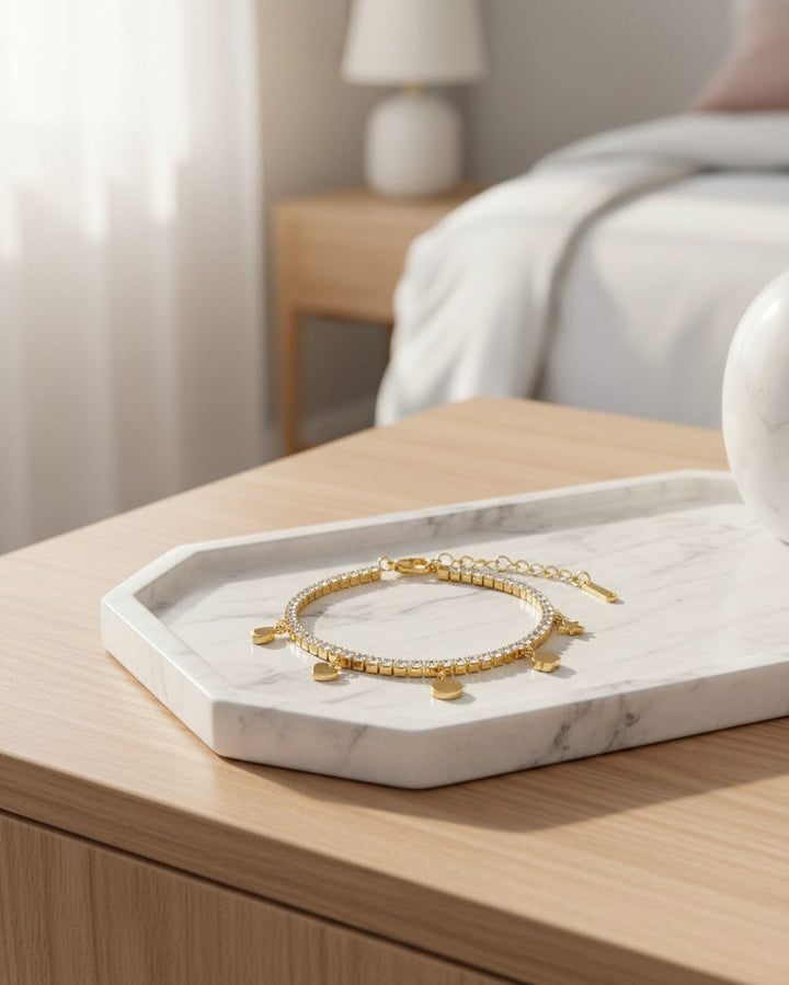 Elli Jewellery gold plated waterproof charm bracelet with crystal accents resting on a white marble tray