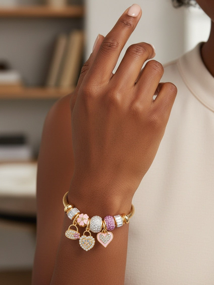 Elli Jewellery gold plated twisted cuff bracelet featuring pink and crystal charm hearts on a model's wrist