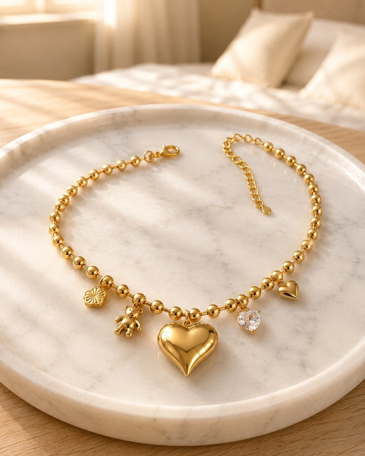 Elli Jewellery gold plated charm necklace featuring a heart, teddy bear, and crystal charm on a beaded chain.