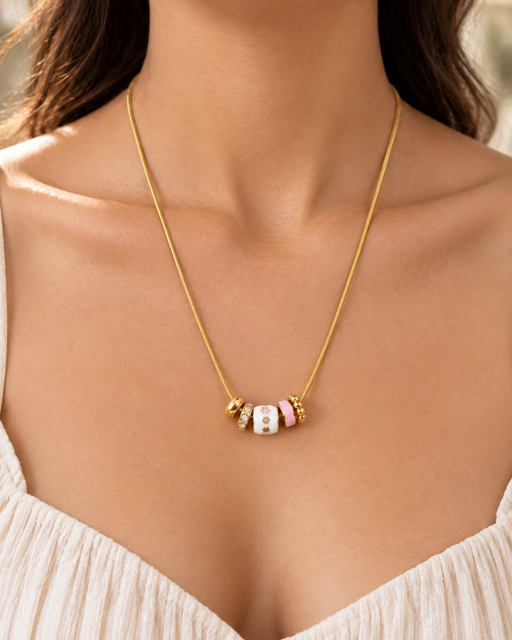 Elli Jewellery gold plated dainty necklace featuring white and pink enamel charms worn on a woman's neck