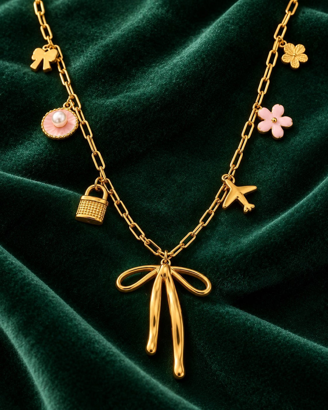Elli Jewellery gold plated charm necklace featuring a ribbon bow, airplane, padlock, and pink flower charms.